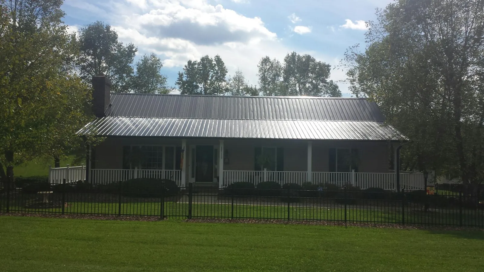 Gray metal roof on a brick ranch with a full width front porch — Gutter Guard Installation work by our crew in Echo
